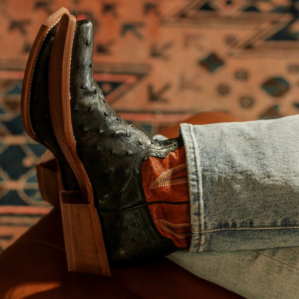 Presentando la bota Rylen Full Quill de 13” en negro y marrón en el modelo.